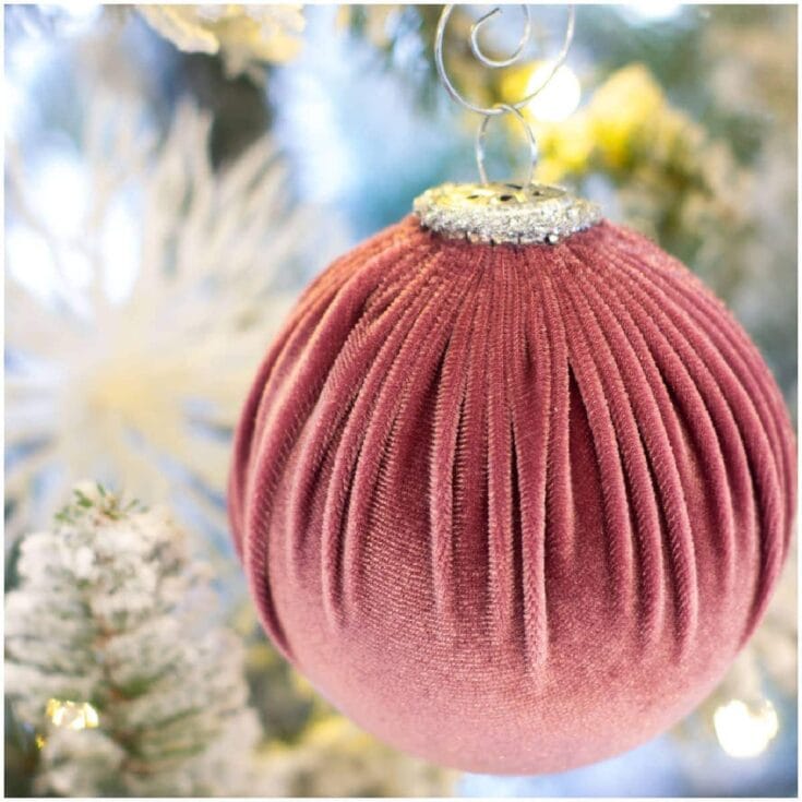 Vintage velvet pink Christmas ornament on decorated tree with silver cap and hanging wire, festive holiday decor for Christmas and seasonal celebrations.