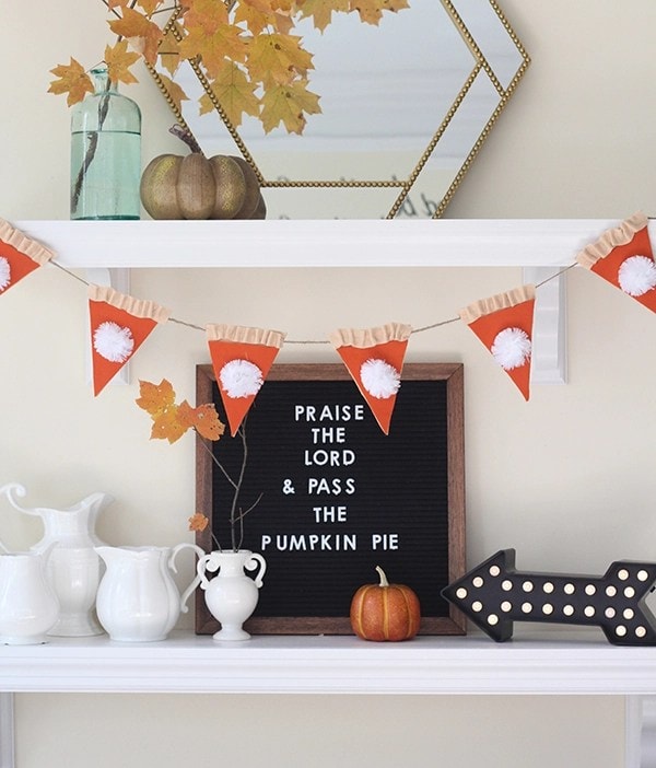 Pumpkin-themed autumn decor with festive banners, white ceramic pitchers, and a decorative arrow sign on a white fireplace mantel - perfect for fall and Thanksgiving celebrations.