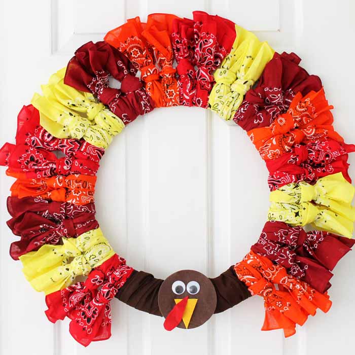 Red, yellow, orange bandana fabric wreath with a turkey face decoration, perfect for Thanksgiving fall home decor, seasonal door wreath, handmade fabric craft, festive holiday decoration, Thanksgiving wreath.
