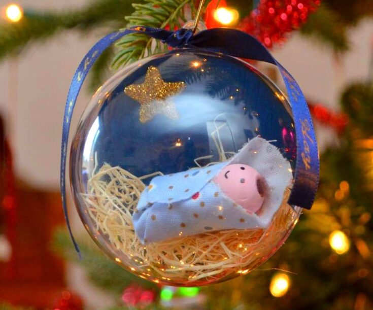 Delicate glass ornament showcasing a tiny cloth piglet nestled in straw with a glittery star, perfect for Christmas tree decoration, symbolizing love and warmth during the holiday season.