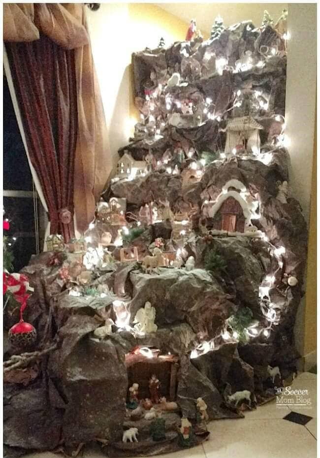 Christmas nativity scene display with figurines, lights, and decorative rocky landscape, creating a festive holiday scene inside the home.