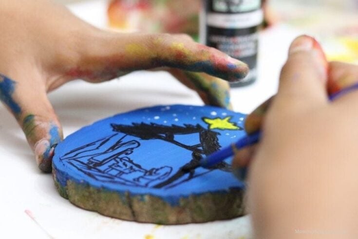 Colorful hand-painted wooden ornament with a nativity scene, featuring vibrant blue background and bright yellow star. Perfect home decor for Christmas and holiday celebrations.