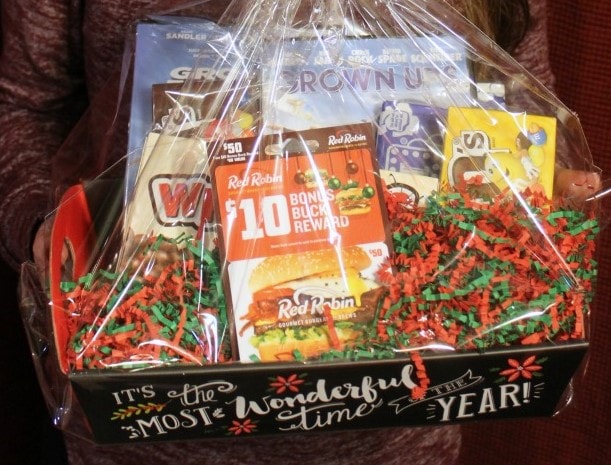 A colorful gift box filled with snack packs and treats, wrapped in clear cellophane with festive red and green paper shred, perfect for holiday gifting or special celebrations.
