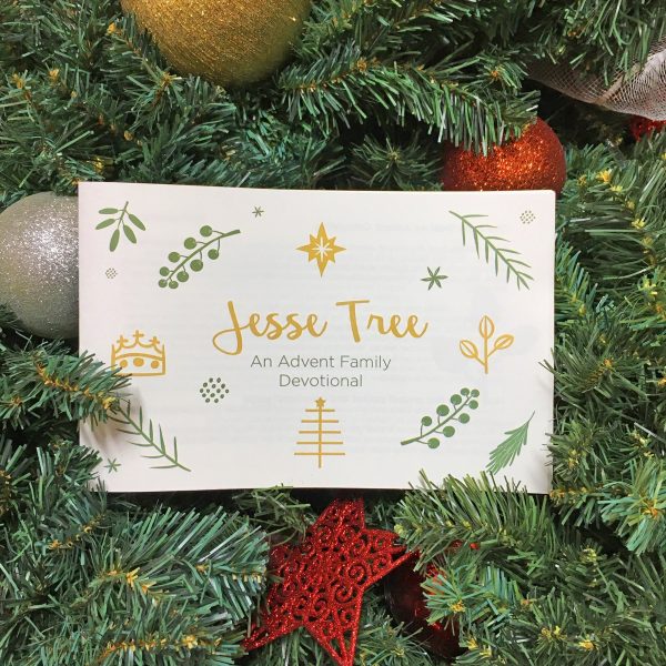 Jesse Tree Advent Family Devotional card nestled in Christmas greenery with ornaments and decorations, encouraging faith-based holiday traditions and spiritual reflection.