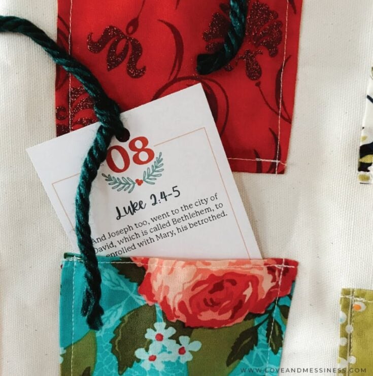Colorful fabric Advent calendar with a floral theme and a biblical scripture card tucked into a pocket, symbolizing faith and celebration during the holiday season.