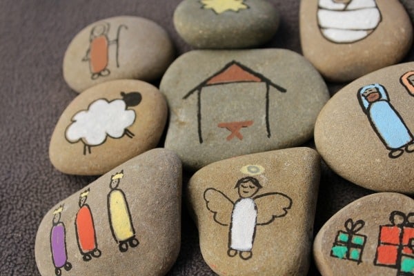 Colorful painted rocks featuring adorable angel, nativity, and holiday-themed illustrations, perfect for inspirational or religious home decor and gifts.