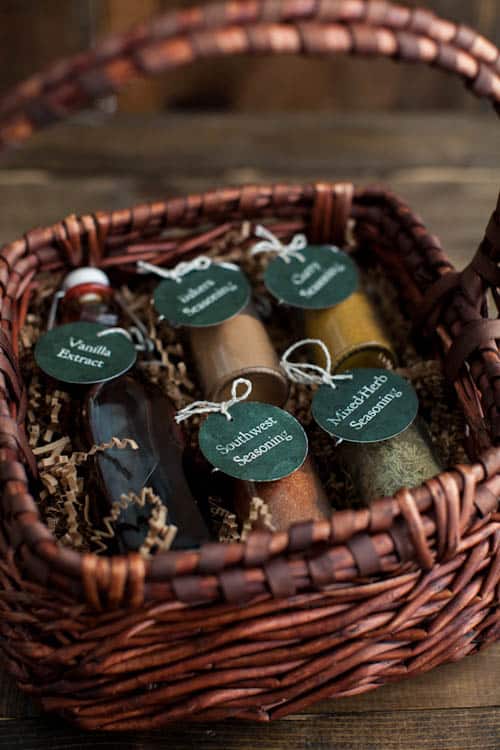 Spice gift set in a woven basket with tags for vanilla extract, southern herbs seasoning, and nutmeg for homemade cooking and seasoning.