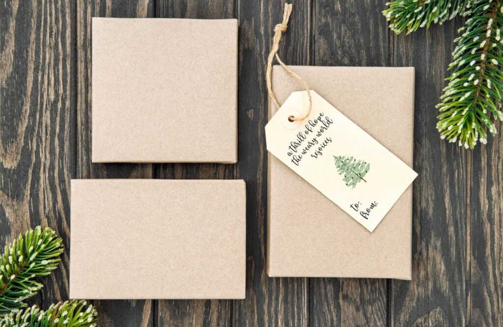 Plain beige gift boxes with a holiday gift tag, on rustic wooden background, perfect for Christmas decoration or gift-giving, part of A Hundred Affections collection.