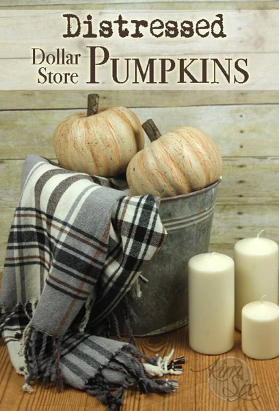 Distressed white pumpkins in a metal bucket with a plaid blanket and white candles, perfect for fall home decor or rustic seasonal displays.