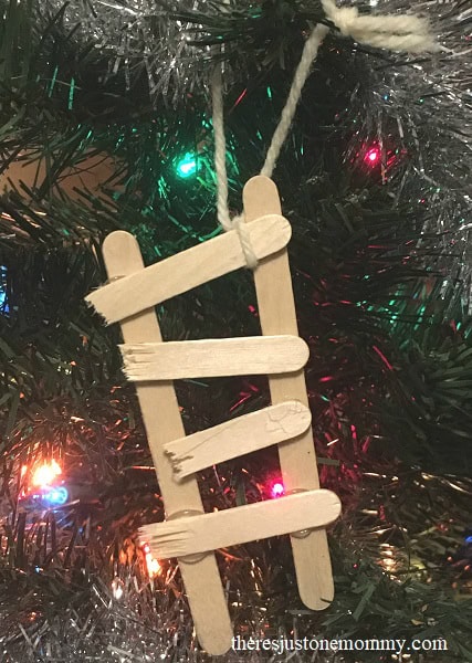 Wooden sled ornament hanging on Christmas tree with colorful lights, holiday decoration, festive Christmas décor, rustic seasonal ornament, handmade wooden craft.