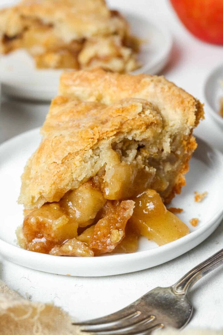 Buttery apple pie filling spilling from a flaky homemade pie crust, tempting and warm, perfect for fall desserts and holiday gatherings.