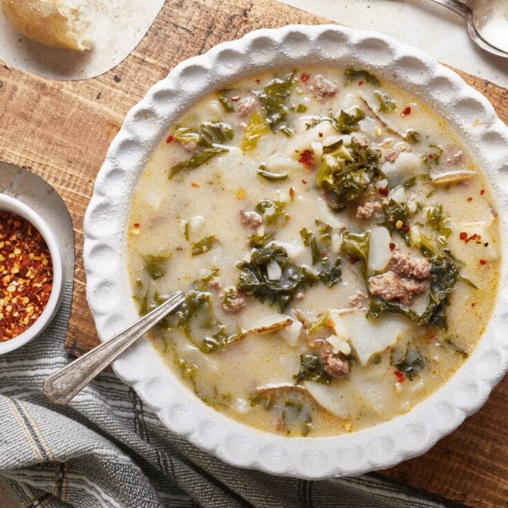 Creamy homemade collard greens soup in a white bowl with a spoon, served on rustic wooden table, highlighting comfort food recipes with fresh greens and hearty broth, perfect for family dinners.