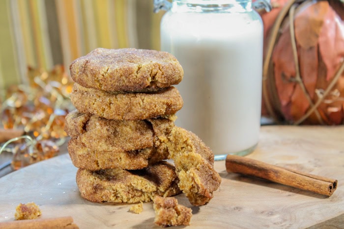 Crispy cinnamon sugar cookies stacked with a broken piece, bottle of milk, cinnamon stick, and festive background - A Hundred Affections.