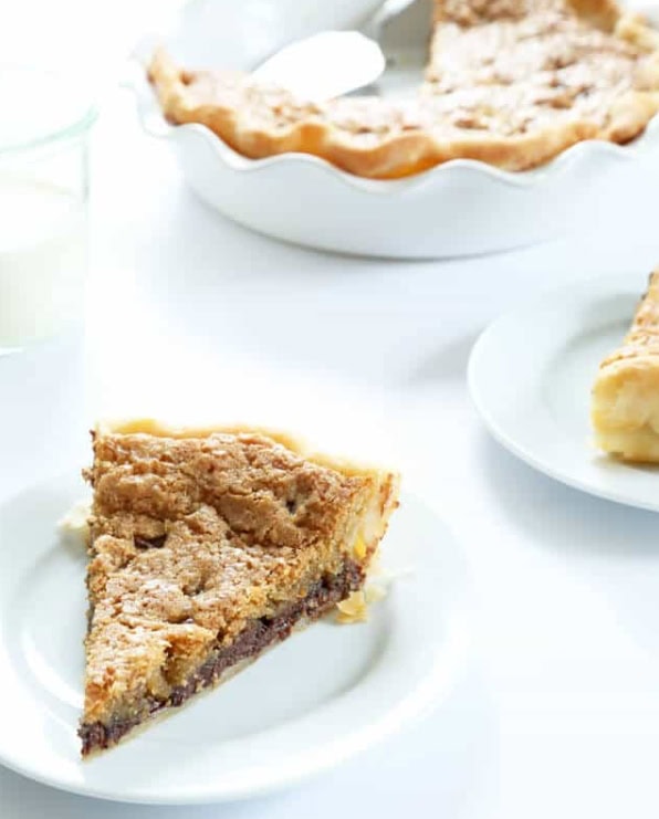 Peach and Apple Pie slice on white plate with whole pie in the background, fresh baked, flaky crust, homemade dessert, perfect for holidays or special occasions.