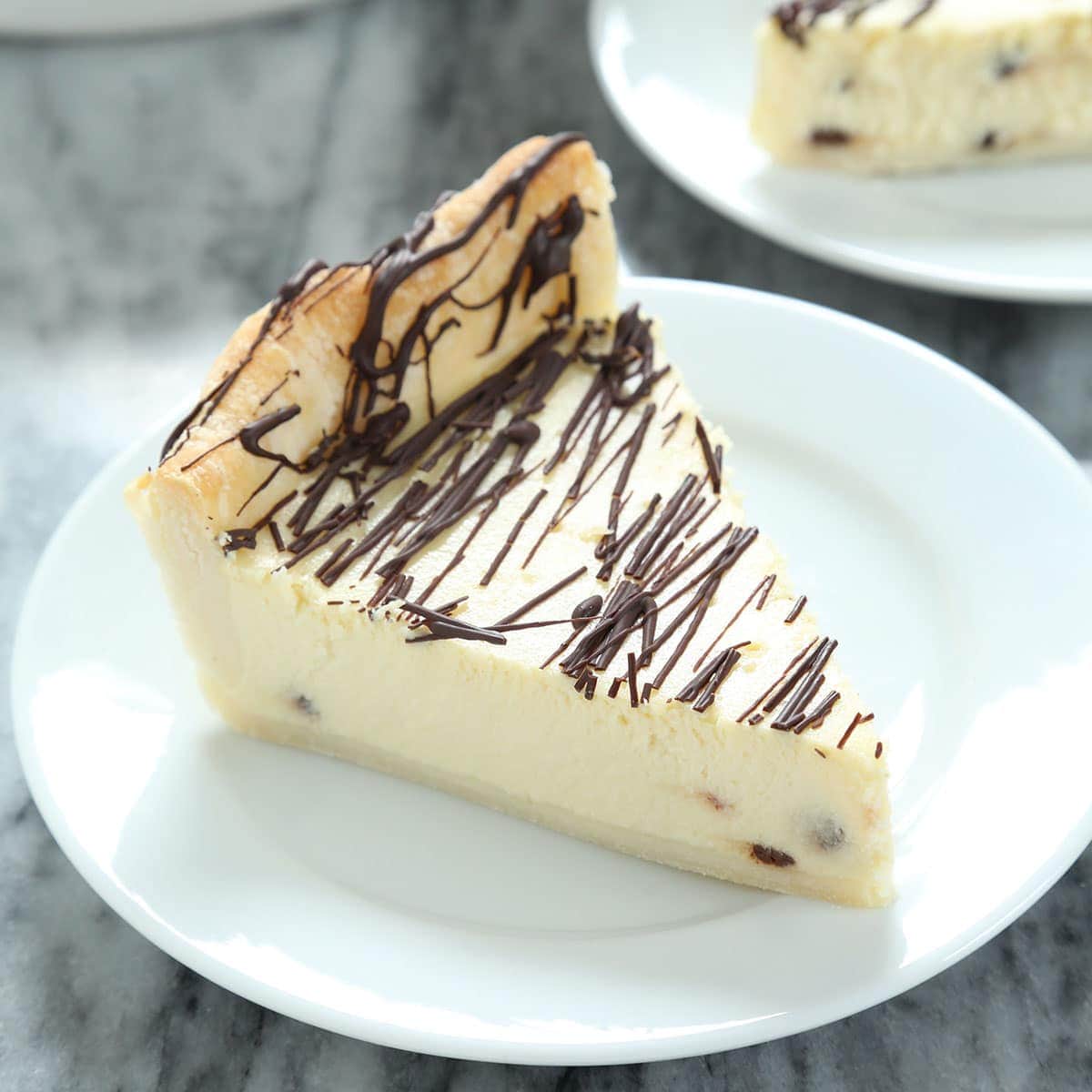 Cheesecake slice with chocolate drizzle on white plate, creamy texture, rich flavor, perfect dessert for celebrations, from A Hundred Affections bakery.