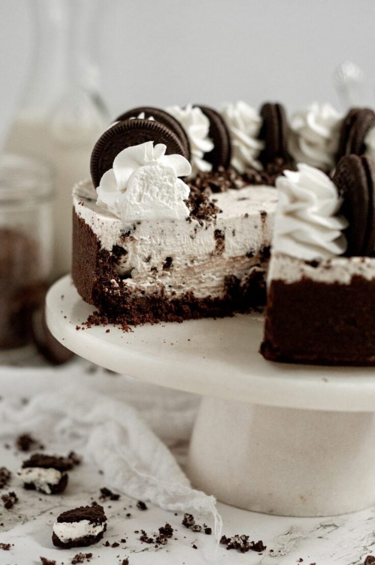 Delicious Oreo cookies and cream cake with chocolate cookies, whipped cream, and chocolate sprinkles on top, displayed on a white cake stand for a celebration or special occasion.