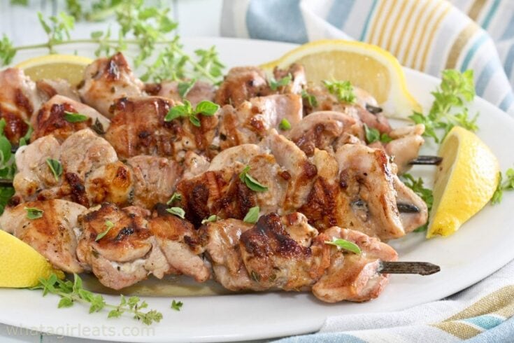 Juicy grilled chicken skewers garnished with fresh herbs and lemon wedges, perfect for a flavorful meal; ideal for summer barbecues and outdoor dining experiences.