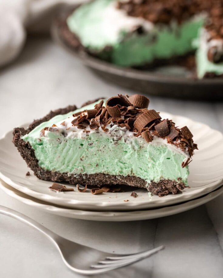 Refreshing mint chocolate pie with chocolate shavings on a white plate, featuring a chocolate cookie crust, creamy filling, and chocolate garnish. Perfect for desserts and special occasions.