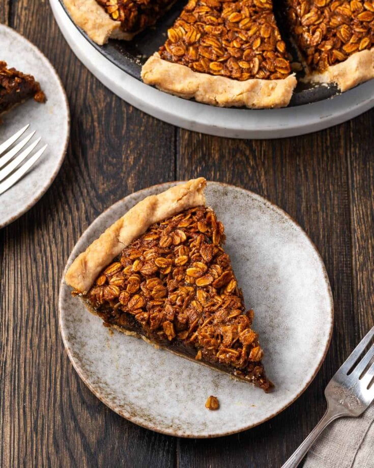 Sweet potato pie with toasted pecans on top, served on rustic ceramic plates. A comforting and classic dessert perfect for holiday gatherings, featuring a flaky crust and rich, spiced filling.