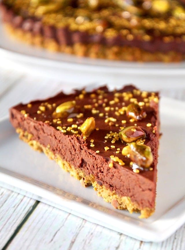 Creamy chocolate pie with pistachio toppings on a white plate, delicious and rich dessert perfect for special occasions or cozy gatherings.