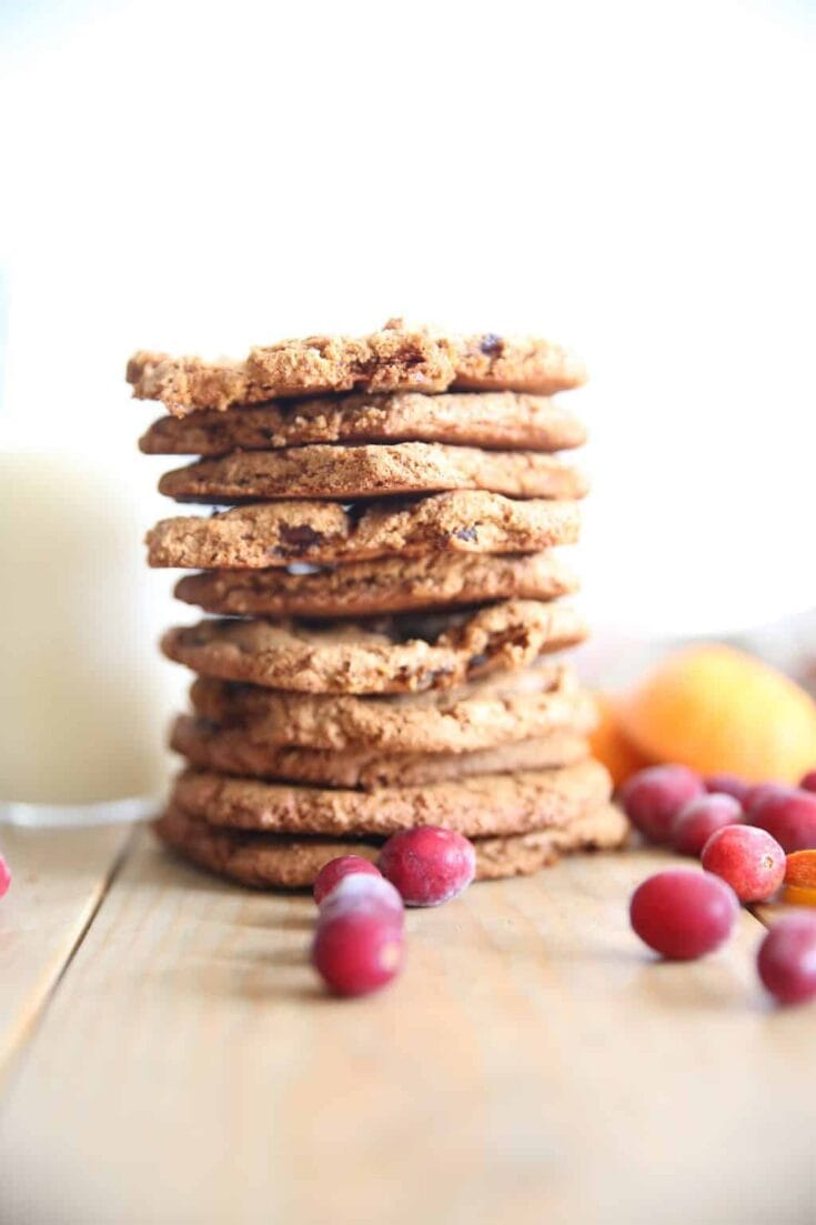 Cookies stacked with berries and a glass of milk on a wooden surface, showcasing homemade chocolate chip cookies – perfect for baked goods, desserts, and holiday treats.