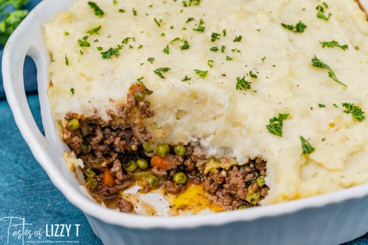 Savory homemade shepherd's pie with mashed potato topping and seasoned ground beef and vegetable filling, garnished with fresh herbs.