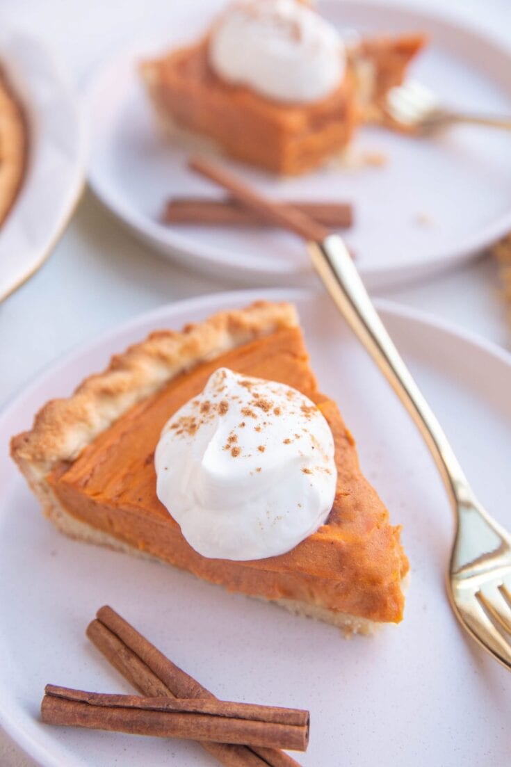 Butterscotch pie slice with whipped cream and cinnamon on a white plate.