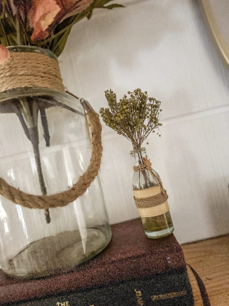 Vase with dried green flowers and glass lantern decor in rustic interior setting, home decor, minimalist style, natural elements, cozy and warm ambiance.