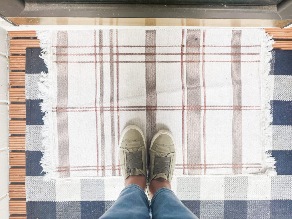 Cozy checkered rugs layered on wooden porch floor, inviting outdoor space with neutral and plaid designs for stylish home decor.