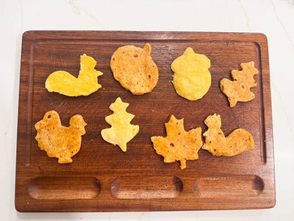 Colorful assorted homemade baked chips on a wooden serving board, served as snack or appetizer, ideal for game day or holiday gatherings.