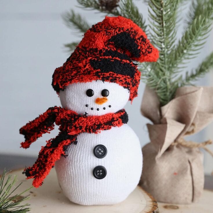 Cute snowman plush toy wearing a red and black striped beanie and scarf, perfect for Christmas winter decor or holiday gift ideas.