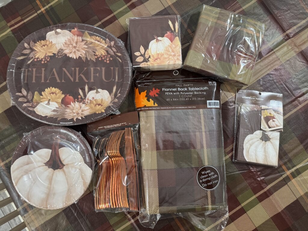 Festive autumn-themed tableware and decorations including pumpkin plates, "Thankful" napkins, fall napkins, disposable cutlery, and fall-themed tablecloths for Thanksgiving or fall celebrations.