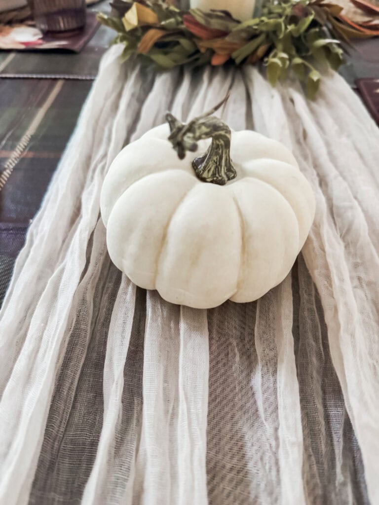 White pumpkin decor with metallic stem, perfect for fall and Thanksgiving seasonal decoration, styled on rustic table runner.
