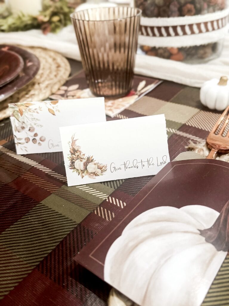 Rustic fall-themed table setting with white pumpkin and "Give Thanks to the Lord" cards for Thanksgiving celebration.