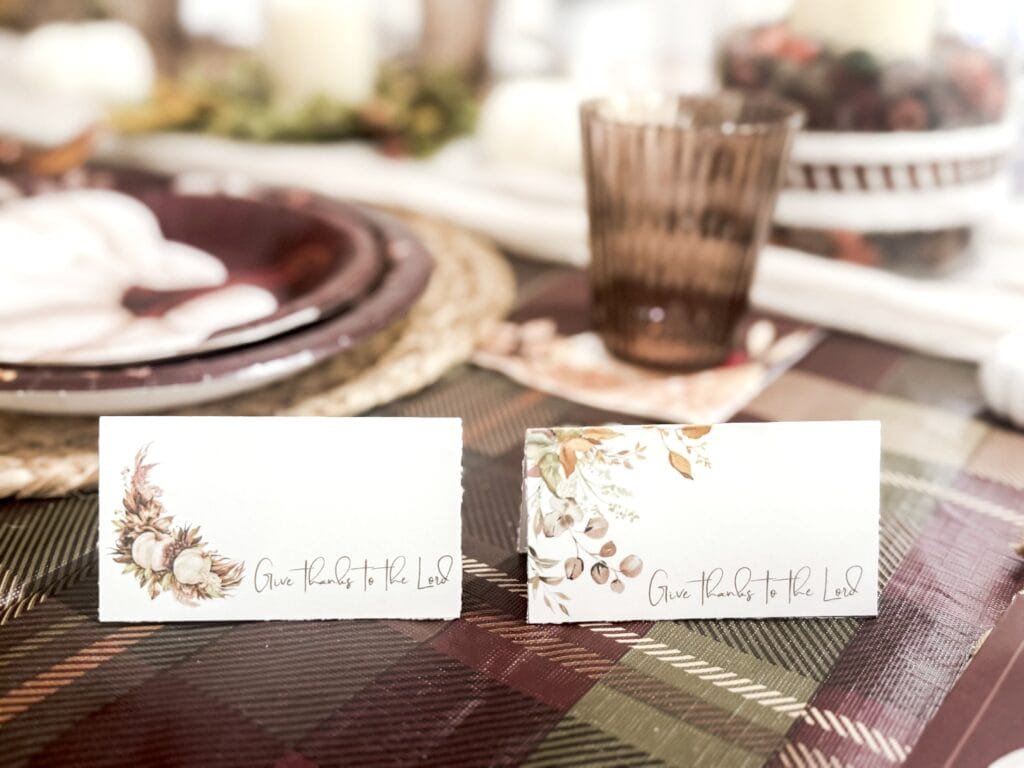 Delicate autumn-themed place cards with "Give Thanks to the Lord" script, featuring floral designs for Thanksgiving table setting.