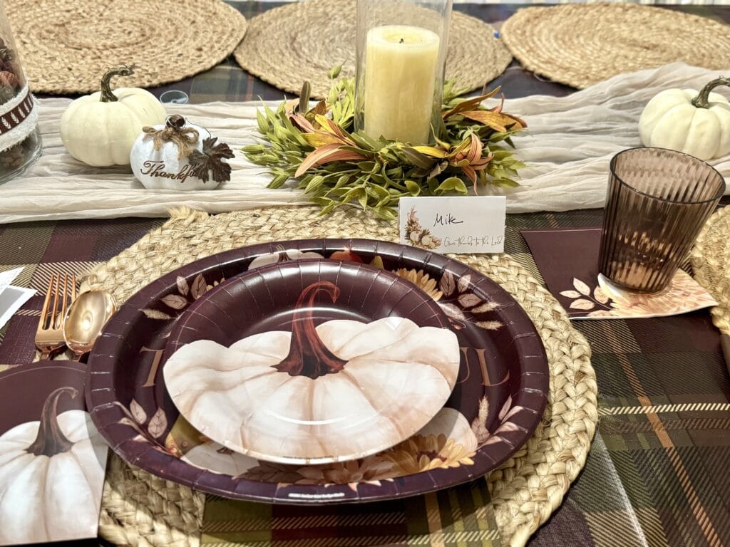 Pumpkin-themed fall table setting with decorative pumpkins, a candle centerpiece, and autumn-inspired tableware for Thanksgiving or harvest celebrations.