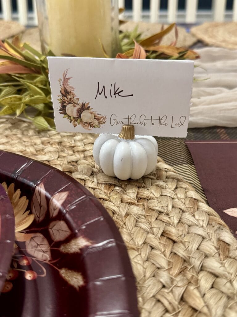 Miniature white pumpkin table favor for fall or Thanksgiving celebration with personalized name card and decorative floral accents, perfect for autumn-themed events and place settings.