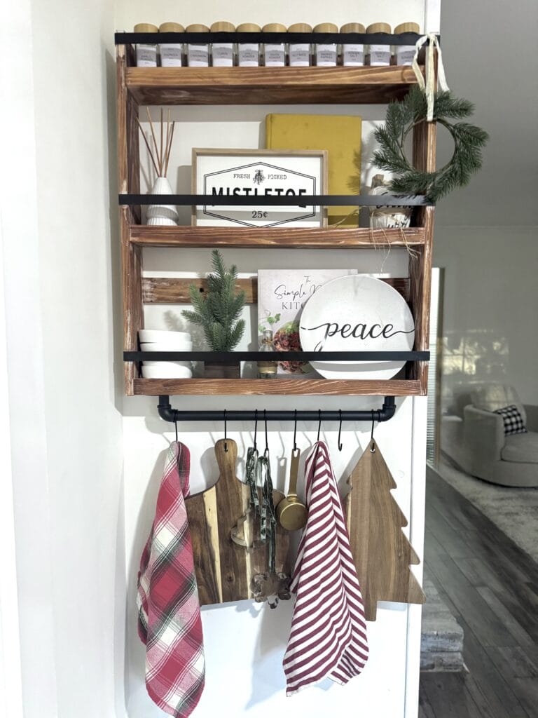 Rustic wooden shelf with holiday decor, kitchen accessories, and greenery.
