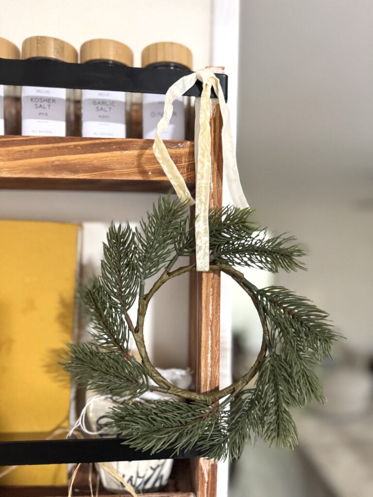 Festive greenery with a rustic wooden ring wreath hanging on a shelf during the holiday season.