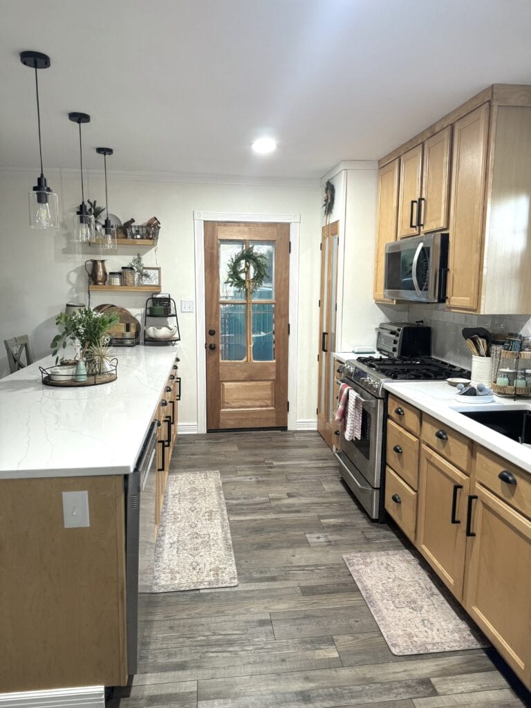 Bright and modern kitchen with natural wood cabinetry, white marble countertops, stainless steel appliances, and cozy decor, perfect for home cooking and family gatherings.