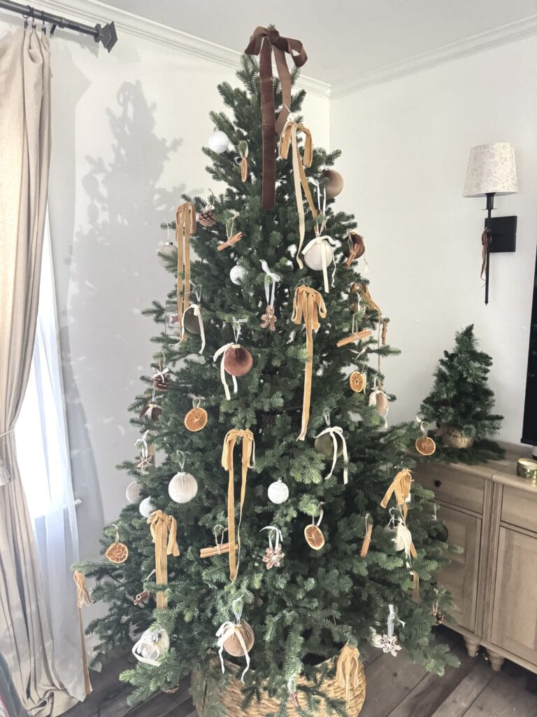 Decorated Christmas tree with rustic, natural ornaments, ribbons, and dried citrus slices, creating a cozy, elegant holiday centerpiece for festive home decor.