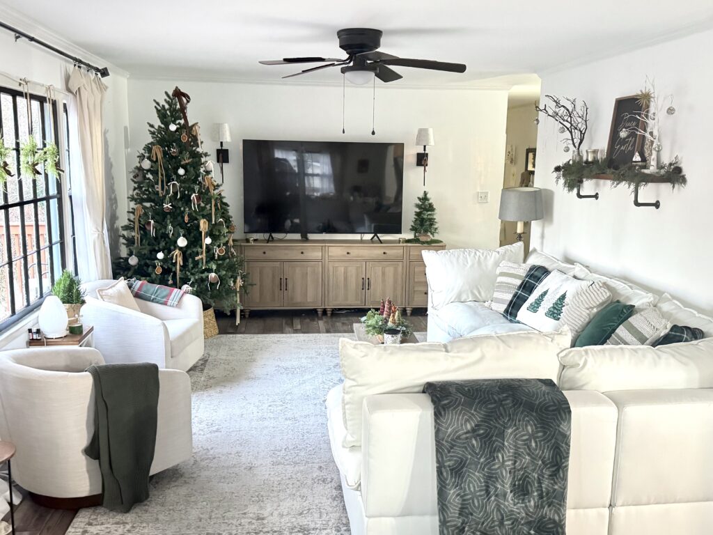 Festive Christmas living room decorated with a tall Christmas tree, cozy seating, holiday pillows, and rustic decor, creating a warm and inviting holiday atmosphere.