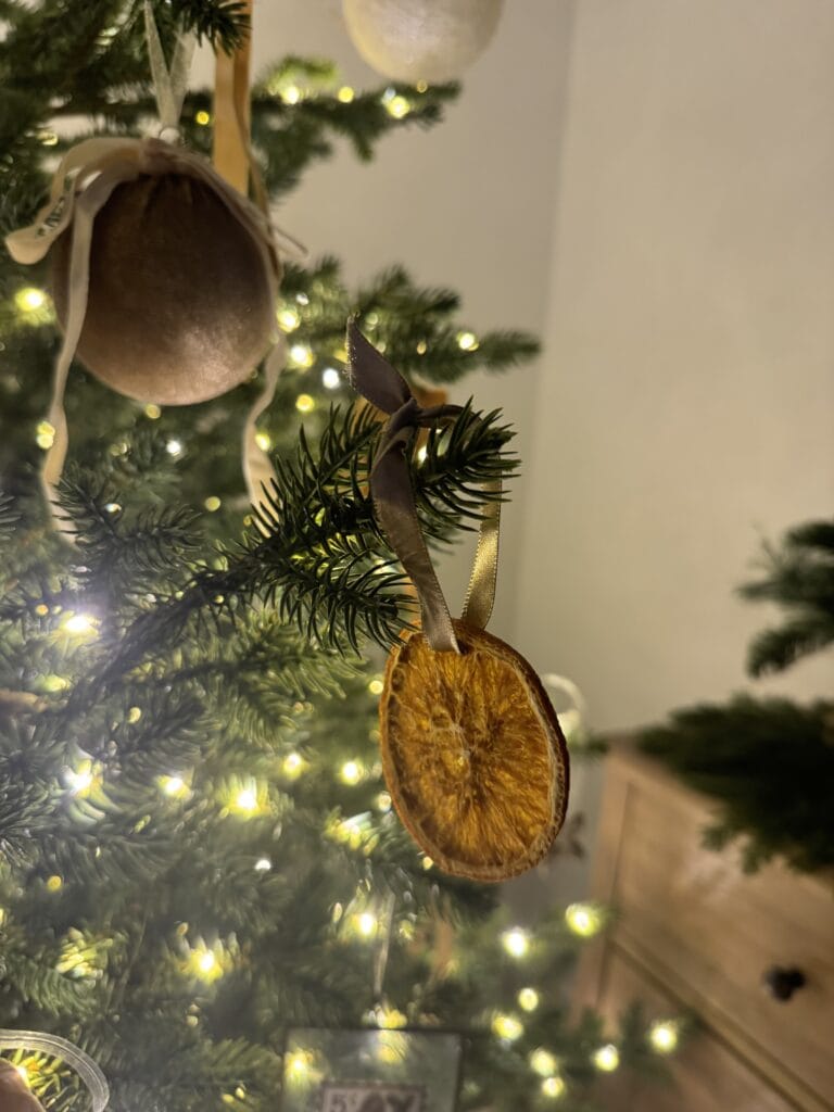 Dried orange slice decoration hanging on a Christmas tree with warm fairy lights, holiday ornament, festive winter decor, natural Christmas ornament, eco-friendly holiday decor.