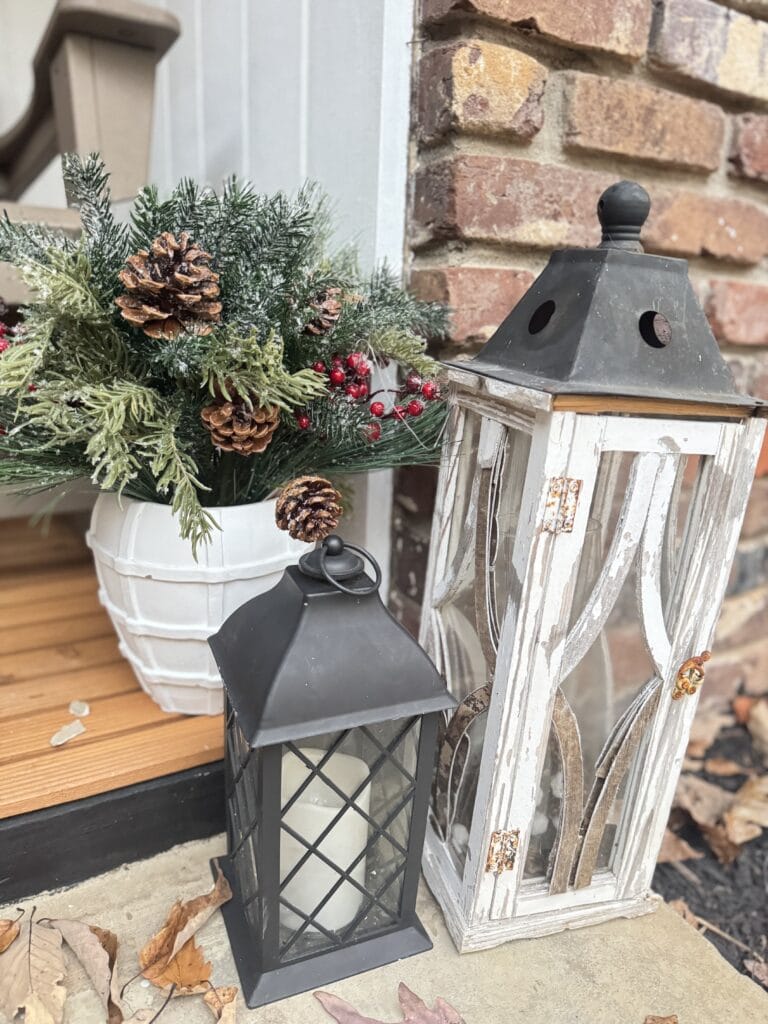 Vintage holiday lanterns and festive winter floral arrangement with pinecones and red berries.