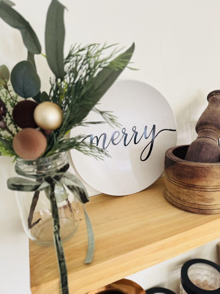Festive holiday flower arrangement with greenery and ornaments, featuring a "merry" sign for Christmas decoration and home decor ideas.