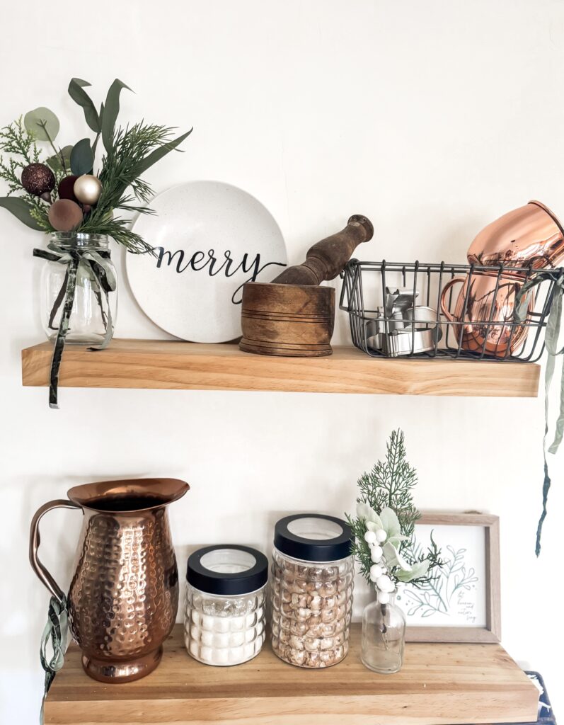 Rustic wooden shelves with holiday decor, greenery, and festive kitchenware, perfect for Christmas home decor and seasonal decorating ideas for a cozy, festive ambiance.