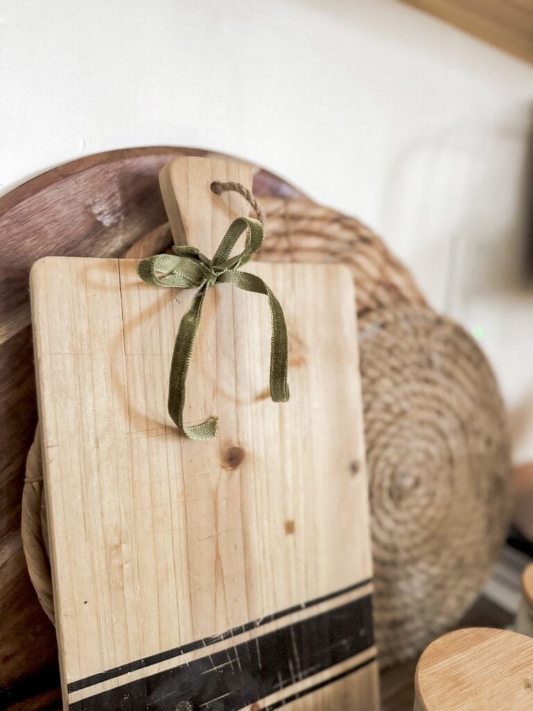 Rustic wooden cutting board with green ribbon bow, natural home decor, cozy farmhouse style, handcrafted kitchen accessory, A Hundred Affections product shot.