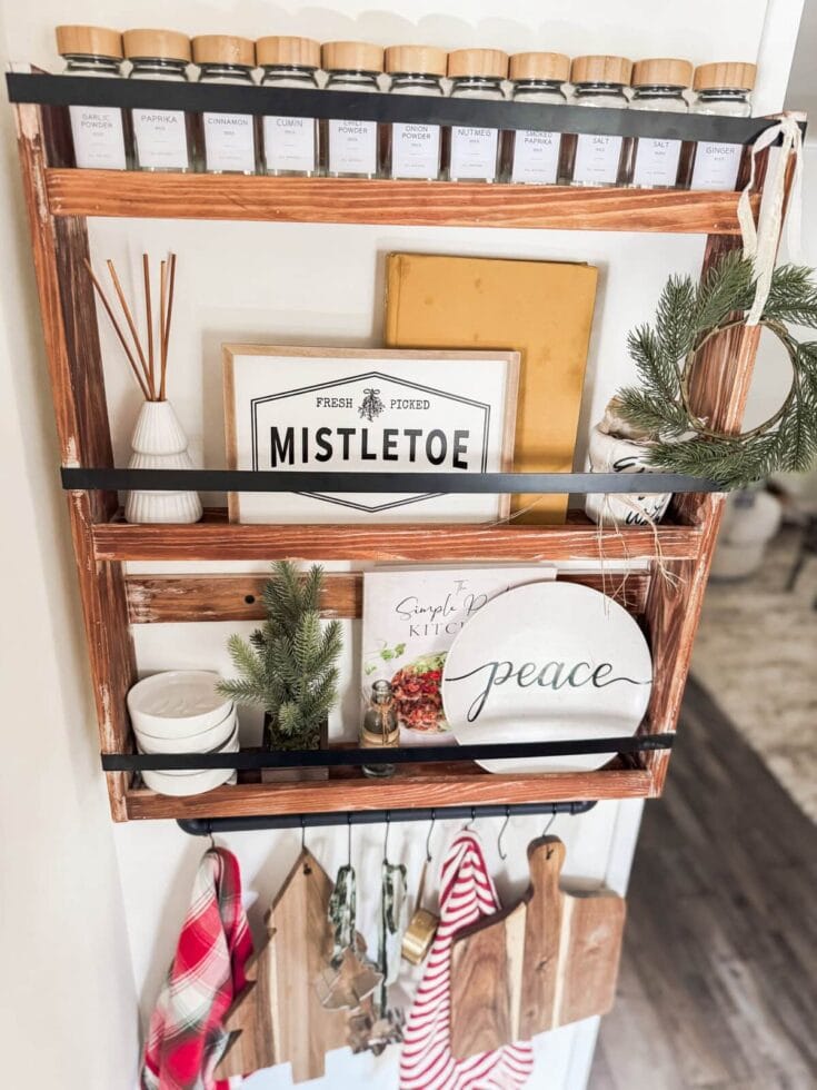 Spice jar shelf with herbs and kitchen decor, wooden spice jars, holiday wreath, and vintage inspired kitchen signs, cozy rustic home decor.