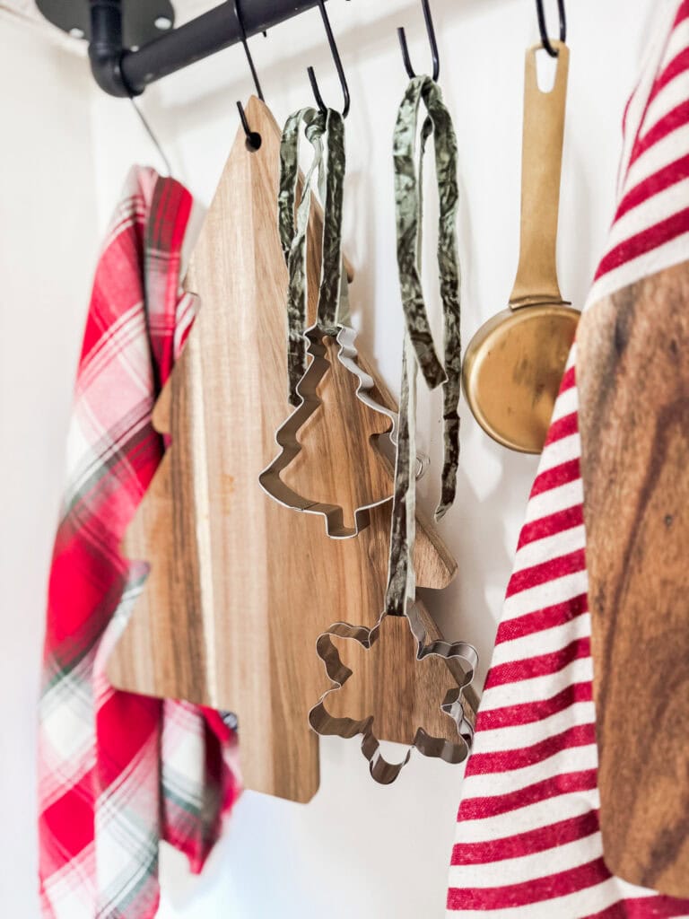 Festive holiday kitchen decor with wooden and metal Christmas cookie cutters, plaid and striped dish towels, showcasing holiday baking essentials.
