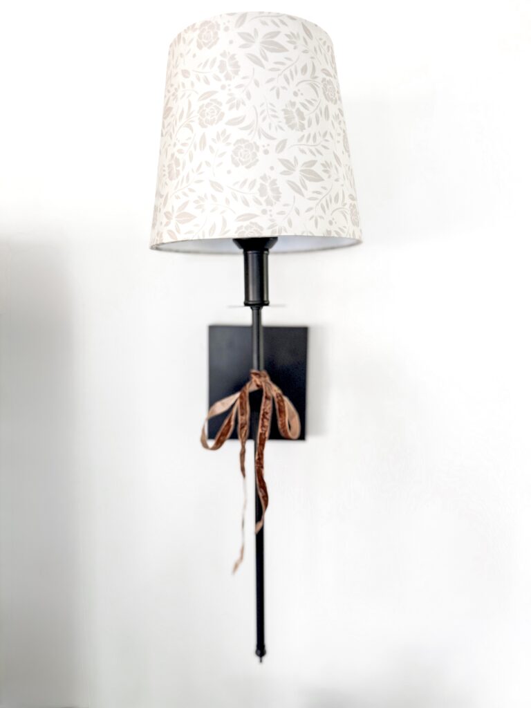 Elegant wall-mounted lamp with floral-patterned lampshade and ribbon accent, perfect for cozy home decor and lighting inspiration.